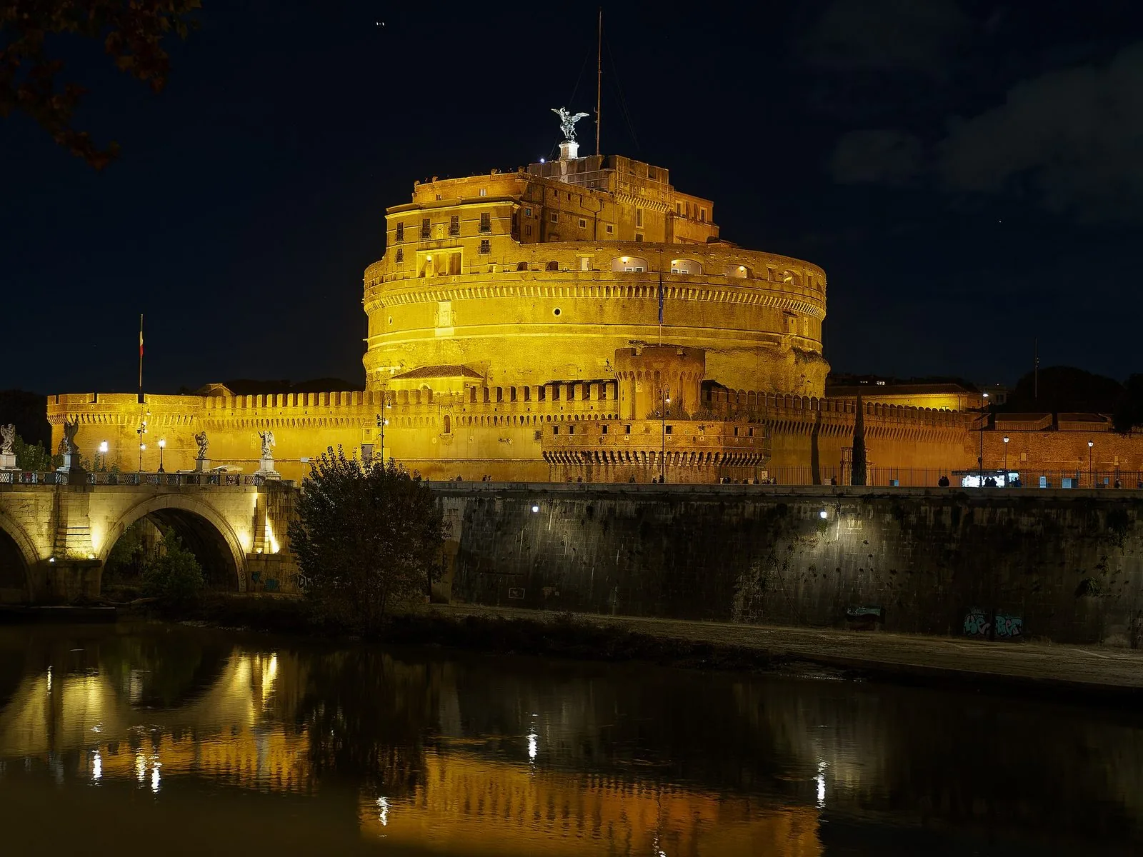 Castel Sant'Angelo illuminato di notte, con Ponte Sant'Angelo a sinistra e le luci riflesse nel Tevere