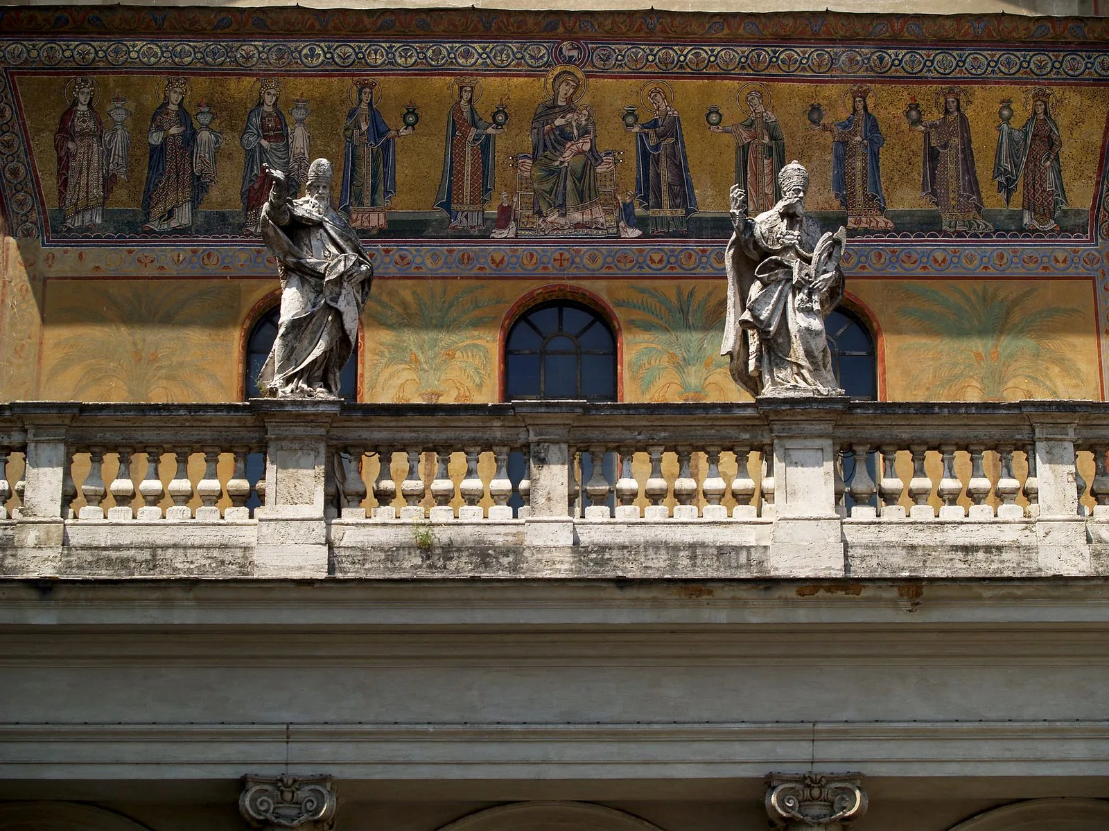 Il mosaico dorato sulla facciata di Santa Maria in Trastevere con la Madonna col Bambino tra figure femminili, sopra la balaustra con due statue di pontefici
